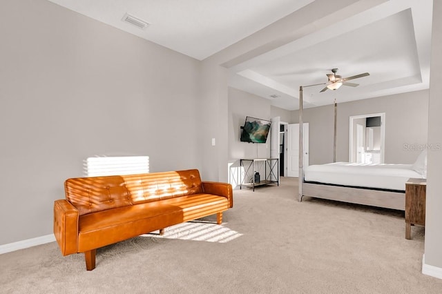 carpeted bedroom with a tray ceiling and ceiling fan