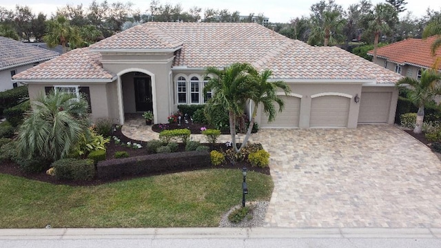 mediterranean / spanish home featuring a garage and a front lawn