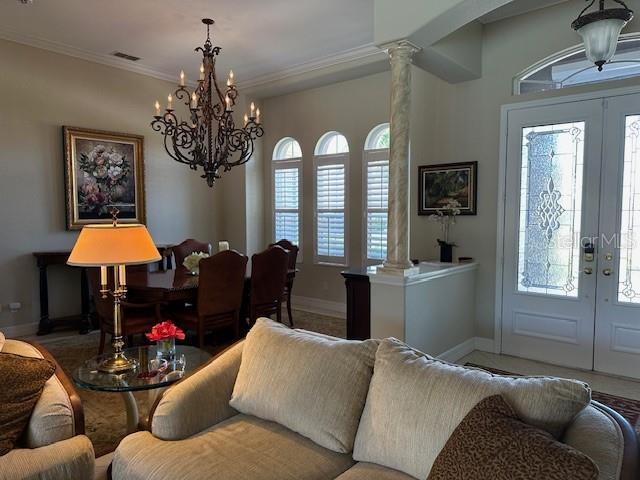 living room with visible vents, decorative columns, baseboards, a chandelier, and french doors