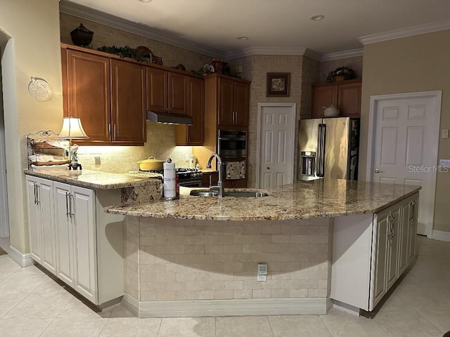 kitchen featuring stainless steel refrigerator with ice dispenser, a sink, light stone counters, multiple ovens, and under cabinet range hood