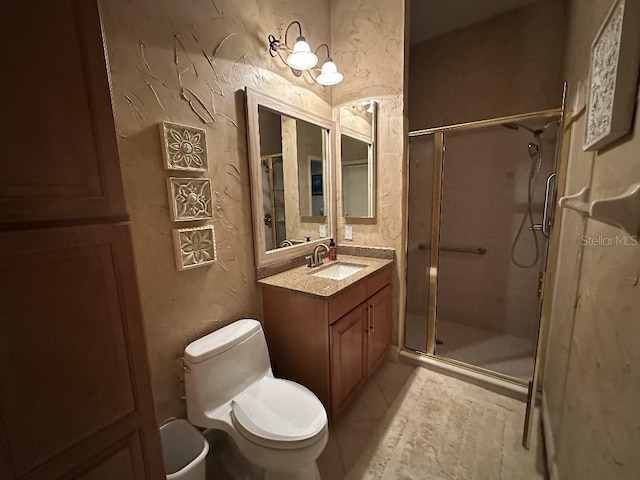 bathroom with toilet, a textured wall, a shower stall, and vanity