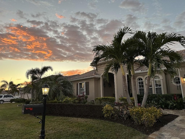 view of front of home with a lawn, stucco siding, and a tiled roof