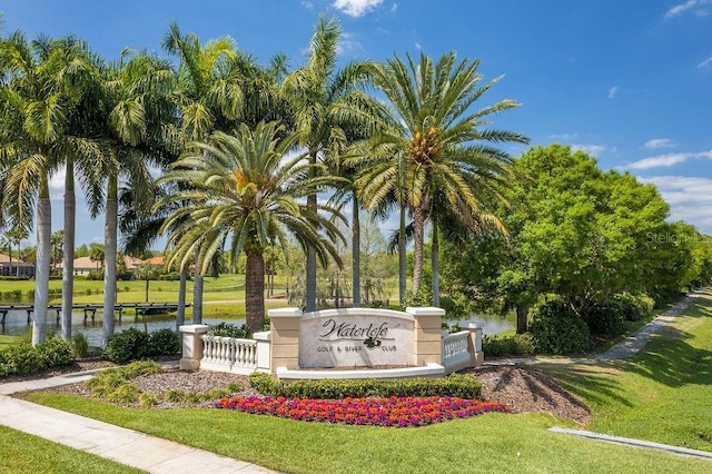 community sign featuring a lawn and a water view