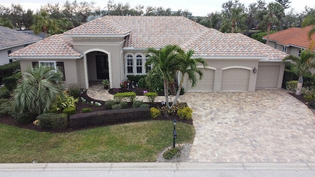 10626 Restoration Ter, Bradenton, FL 34212 - mediterranean / spanish-style home featuring an attached garage, a tiled roof, driveway, stucco siding, and a front yard