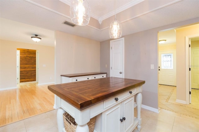 kitchen featuring butcher block counters, white cabinetry, a kitchen island, pendant lighting, and light tile patterned floors