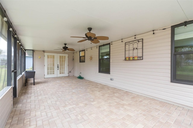 unfurnished sunroom featuring ceiling fan and french doors