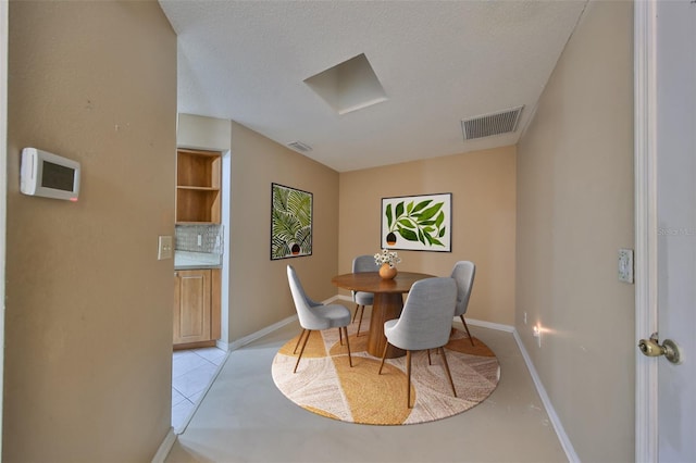 dining area featuring a textured ceiling and light tile patterned flooring