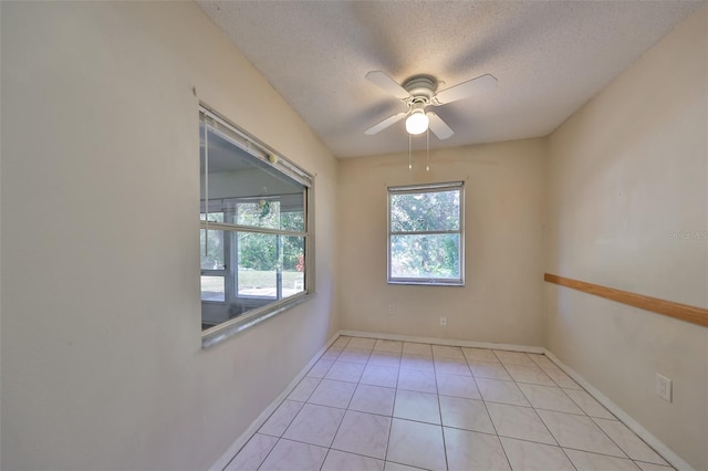 spare room featuring ceiling fan, light tile patterned flooring, a textured ceiling, and a wealth of natural light