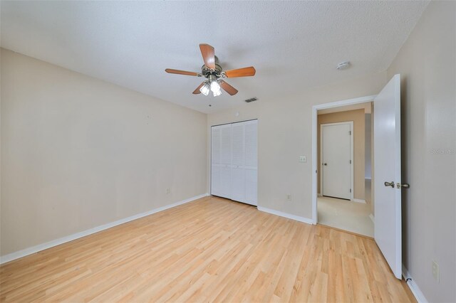 unfurnished bedroom with ceiling fan, light hardwood / wood-style floors, a textured ceiling, and a closet