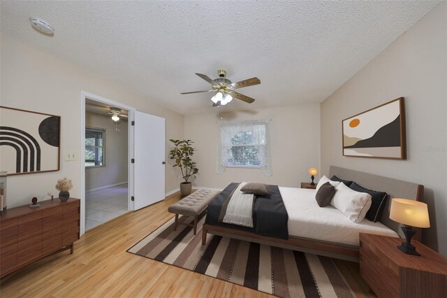 bedroom featuring ceiling fan, a textured ceiling, and light hardwood / wood-style flooring