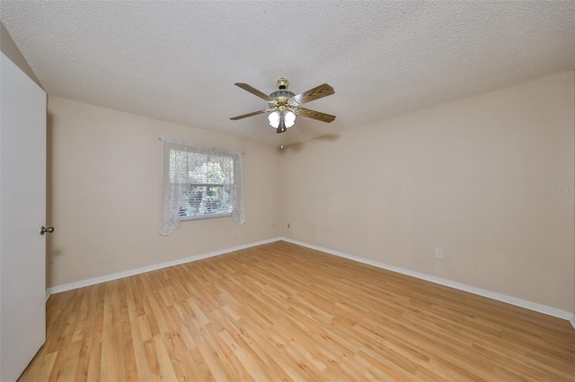 empty room featuring ceiling fan, light wood-type flooring, and a textured ceiling