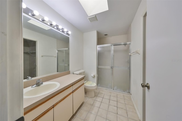 bathroom with a skylight, tile patterned floors, an enclosed shower, vanity, and toilet