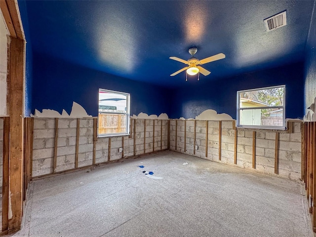 unfurnished room with ceiling fan and a textured ceiling