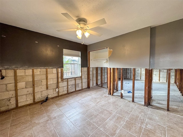 unfurnished room with ceiling fan and a textured ceiling