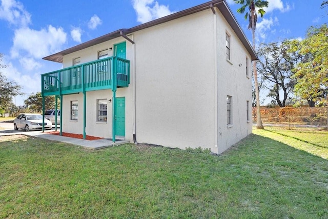 back of property with a yard and a balcony