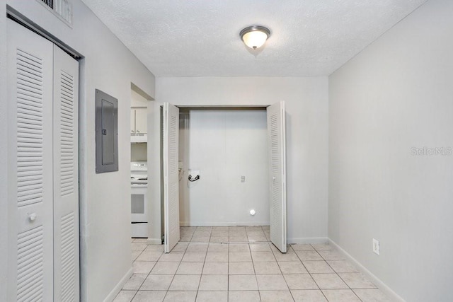 corridor with light tile patterned floors, a textured ceiling, and electric panel