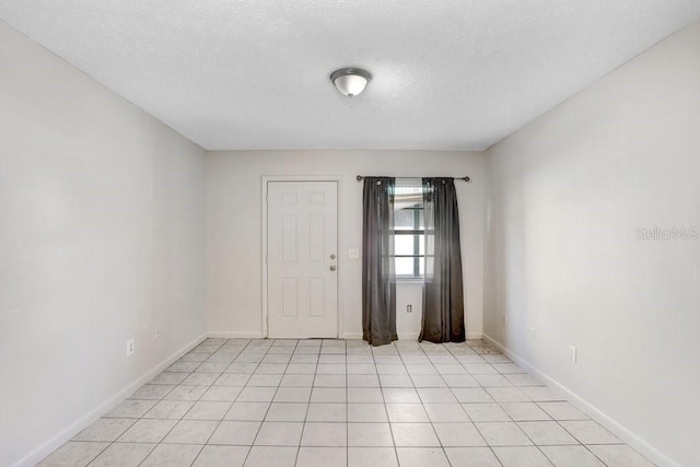 empty room featuring light tile patterned floors and a textured ceiling