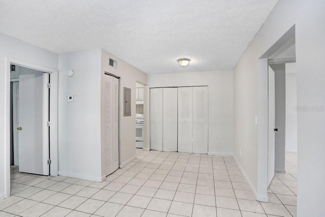 corridor with light tile patterned floors and a textured ceiling