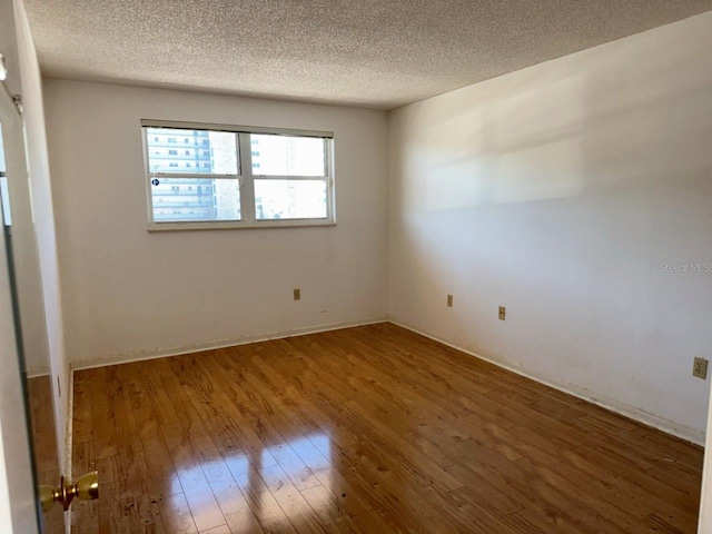 empty room with wood-type flooring and a textured ceiling