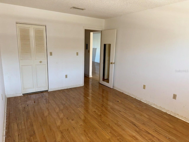 unfurnished bedroom with hardwood / wood-style flooring, a textured ceiling, and a closet