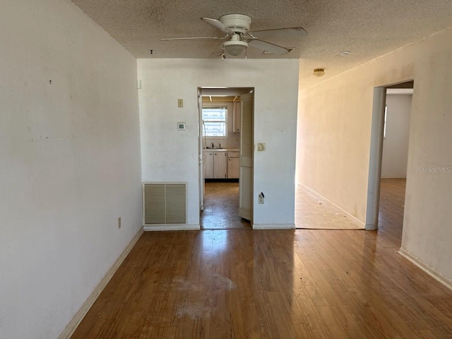 empty room featuring hardwood / wood-style floors, a textured ceiling, and ceiling fan