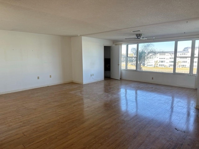 unfurnished room featuring dark hardwood / wood-style floors, ceiling fan, and a textured ceiling