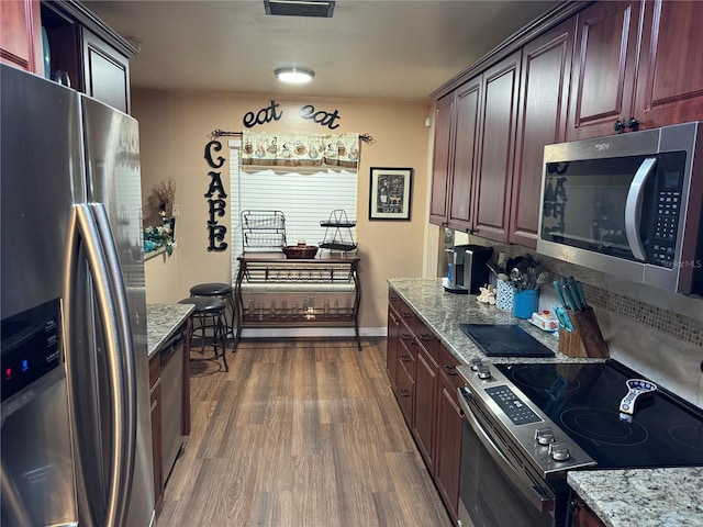 kitchen featuring light stone countertops, appliances with stainless steel finishes, and dark wood-type flooring