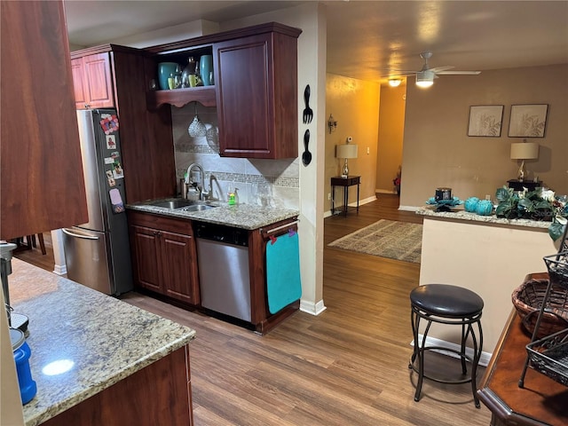 kitchen with appliances with stainless steel finishes, backsplash, ceiling fan, sink, and wood-type flooring