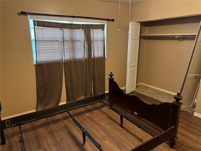 bedroom with multiple windows, dark wood-type flooring, and a closet