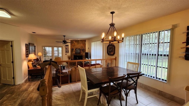 dining area featuring ceiling fan with notable chandelier and a textured ceiling