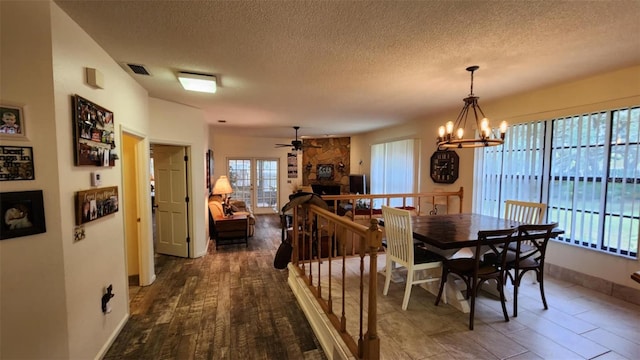 dining room with ceiling fan with notable chandelier, a textured ceiling, and dark hardwood / wood-style flooring