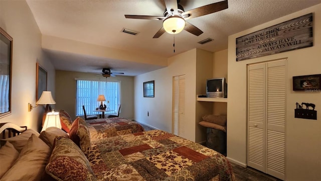 bedroom with ceiling fan, a textured ceiling, and two closets