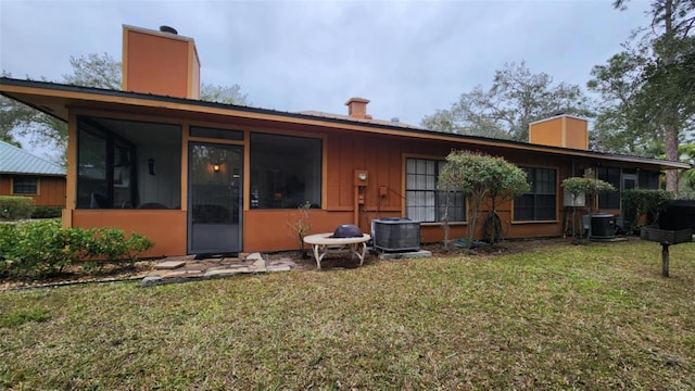 rear view of house featuring a sunroom, a yard, and cooling unit