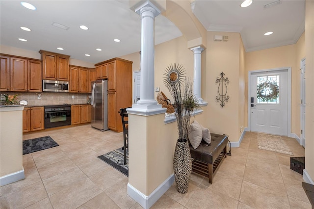 kitchen with backsplash, ornamental molding, stainless steel appliances, and decorative columns