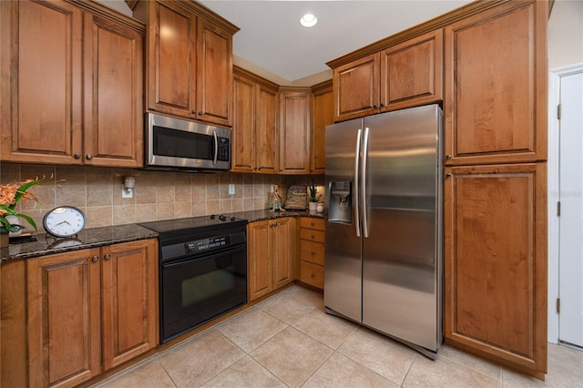 kitchen with dark stone counters, backsplash, light tile patterned floors, and stainless steel appliances