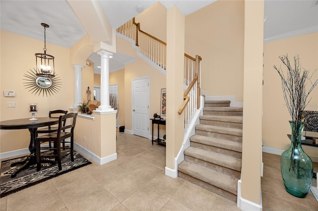 entryway featuring ornate columns, light tile patterned flooring, a chandelier, and ornamental molding