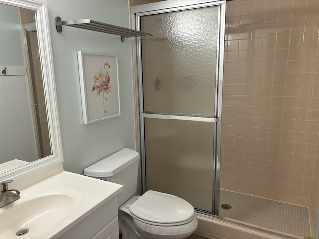 bathroom featuring vanity, toilet, and a shower with door