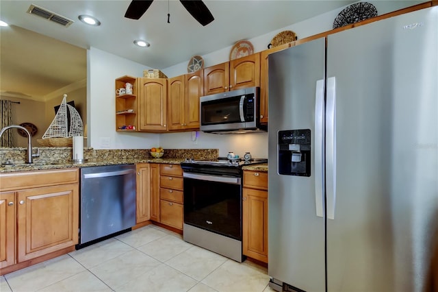 kitchen featuring stainless steel appliances, ceiling fan, sink, light tile patterned floors, and dark stone countertops