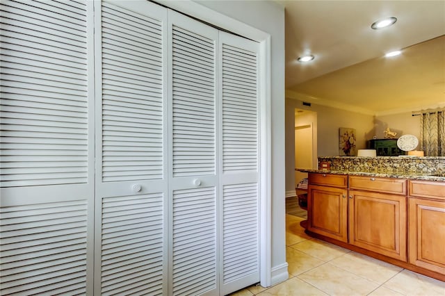 interior space with stone countertops, ornamental molding, and light tile patterned flooring