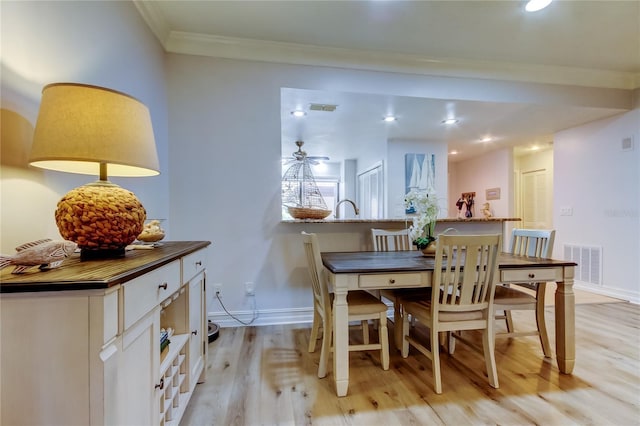 dining room with ceiling fan, light wood-type flooring, and crown molding