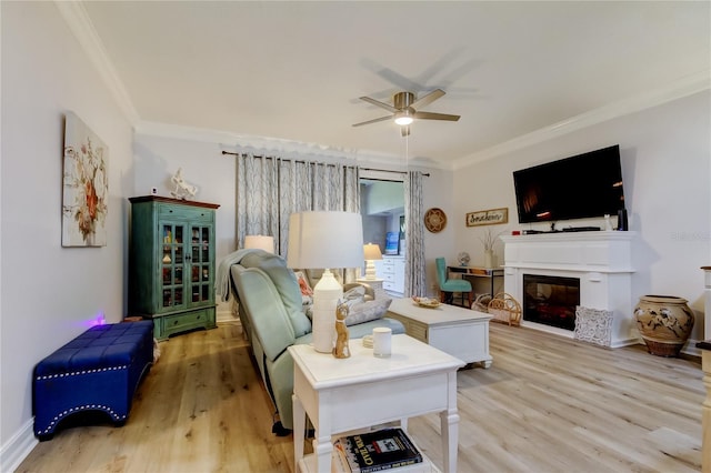 living room with ceiling fan, light wood-type flooring, and ornamental molding