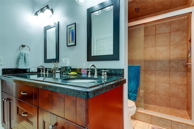 bathroom featuring tile patterned flooring, a tile shower, vanity, and toilet