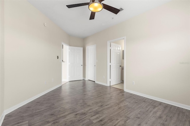 spare room featuring dark wood-style floors, ceiling fan, visible vents, and baseboards