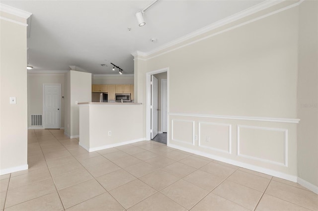 empty room featuring light tile patterned floors, ornamental molding, rail lighting, and visible vents