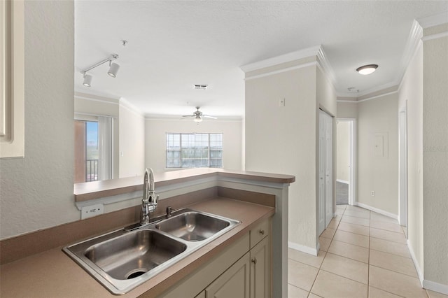 kitchen featuring ornamental molding, light tile patterned flooring, a sink, track lighting, and baseboards