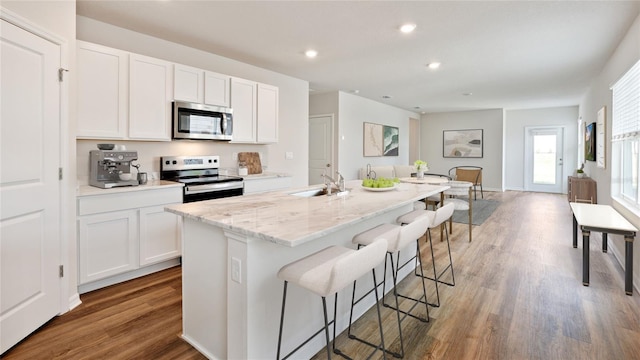 kitchen with stainless steel appliances, white cabinetry, a kitchen island with sink, and sink