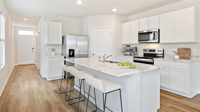 kitchen with white cabinets, a center island with sink, and stainless steel appliances