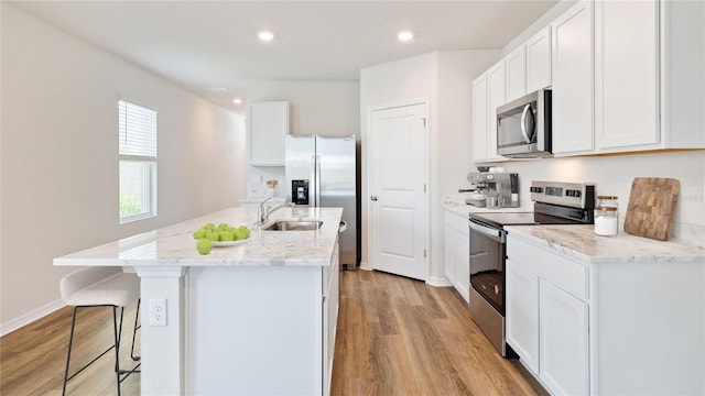 kitchen featuring white cabinets, appliances with stainless steel finishes, a kitchen island with sink, and sink