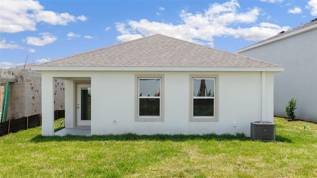 rear view of house featuring a lawn and central air condition unit