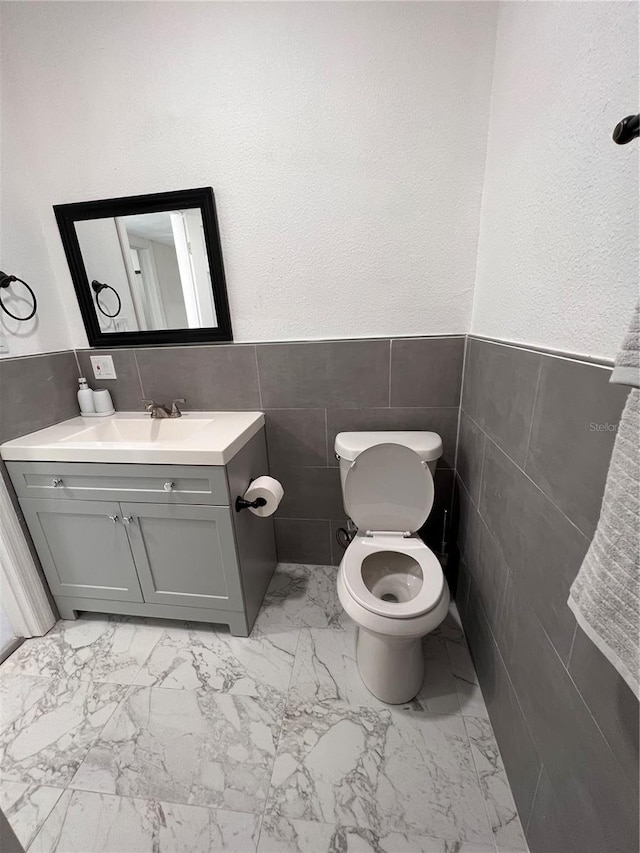 bathroom with vanity, tile walls, and toilet